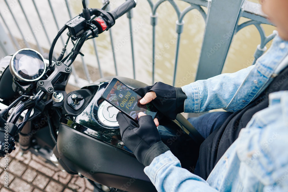 Man sitting on motorcycle and ordering food delivery via application on smartphone Man sitting on motorcycle and ordering food delivery via application on smartphone