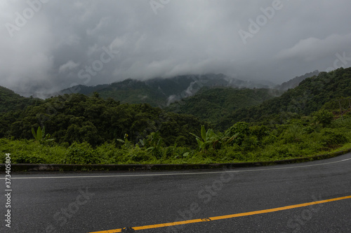 Logistic concept aerial view of countryside road - motorway passing through the serene lush greenery and foliage tropical rain forest mountain landscape © Kittiphat