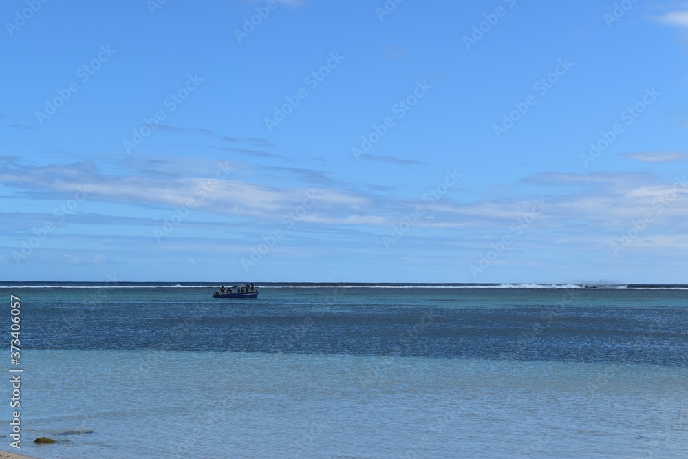Beautiful picture of a tropical lagoon with in background a fishing boat and waves breaking on the reef