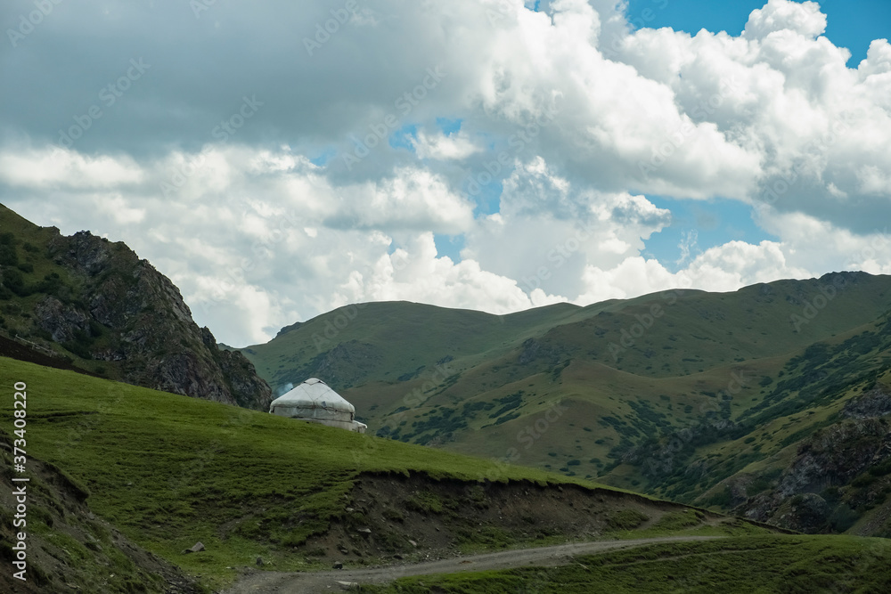 Beautiful green mountains with national Kazakh yurt and cloudy blue sky background. Blue sky. Traditional nomadic life concept.
