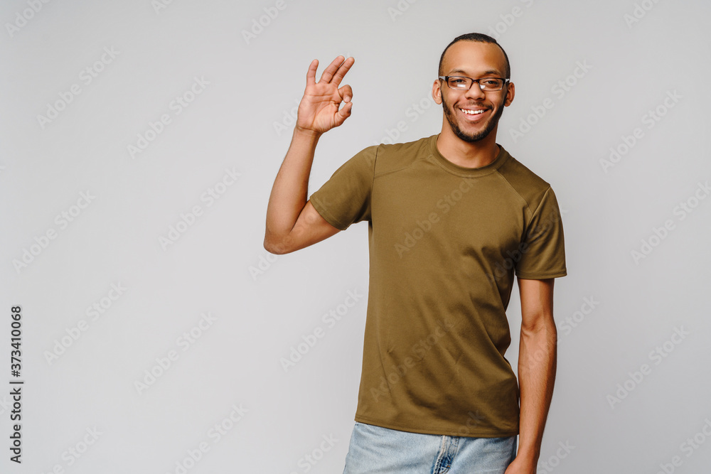 Joyful friendly african-american young man in green t-shirt showing OK sign