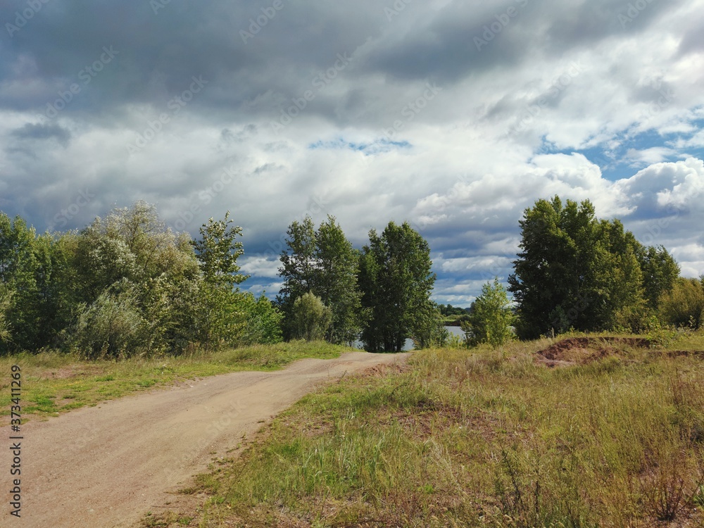 country road with trees and cloudy stormy sky