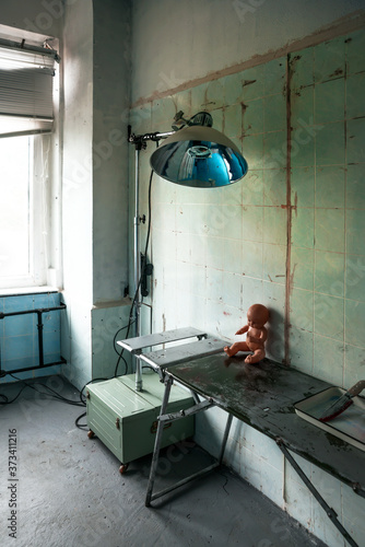 Abandoned operating room with lamp and equipment in an old hospital photo