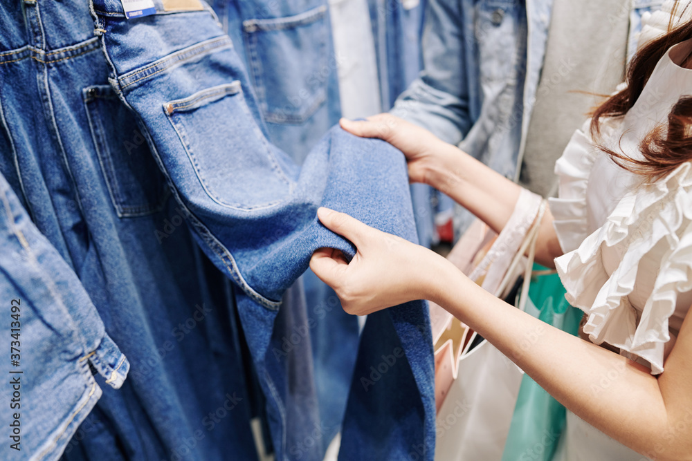 Close-up image of young woman choosing jeans in department store
