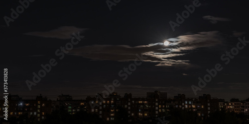 Moon in the night sky in a big city