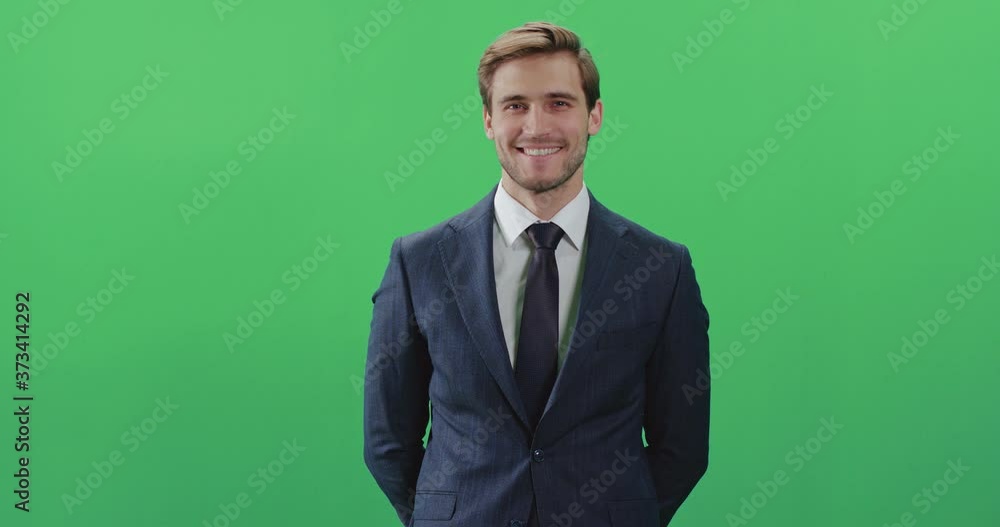 Businessman in a suit standing in green room and looks at the camera, chroma key background, a man smiles, positive emotions. Businessman in a suit standing in green room and looks at the camera, chroma key background, a man smiles, positive emotions.