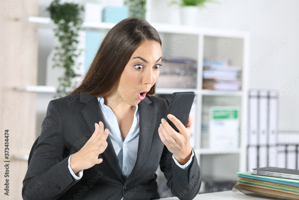 Amazed executive woman checking phone at office Amazed executive woman checking phone at office