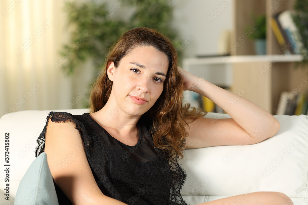 Serious woman posing looking at camera sitting at home Serious woman posing looking at camera sitting at home