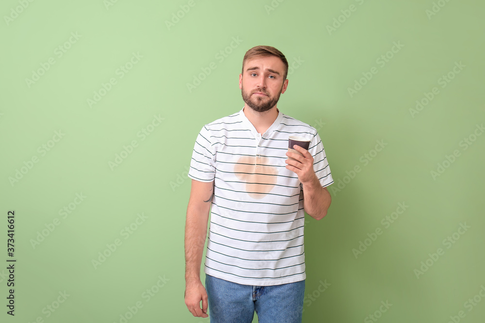 Stressed young man with coffee stains on his t-shirt on color background Stressed young man with coffee stains on his t-shirt on color background