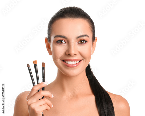 Beautiful young woman with makeup brushes on white background
