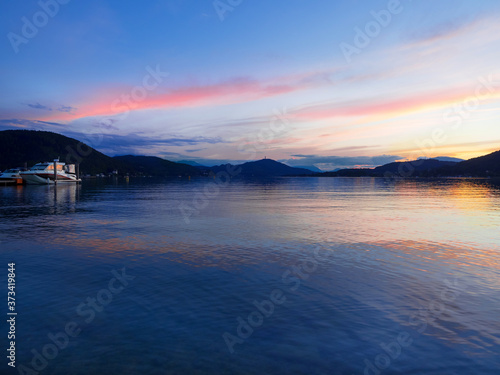 Summer night mountain landscape with boat on Lake Woerther, Carinthia, Austria. Beautiful view of the lakes at sunset in Klagenfurt.