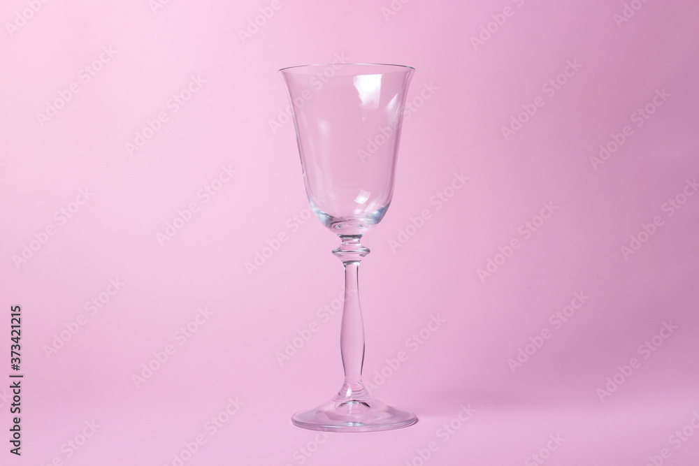 Glass goblet on a pink background. There is a place for writing or logo on the glass Glass goblet on a pink background. There is a place for writing or logo on the glass