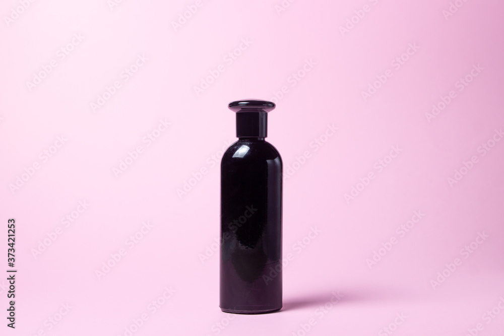 Black bottle on a pink background. There is space for a lettering or logo on the bottle Black bottle on a pink background. There is space for a lettering or logo on the bottle