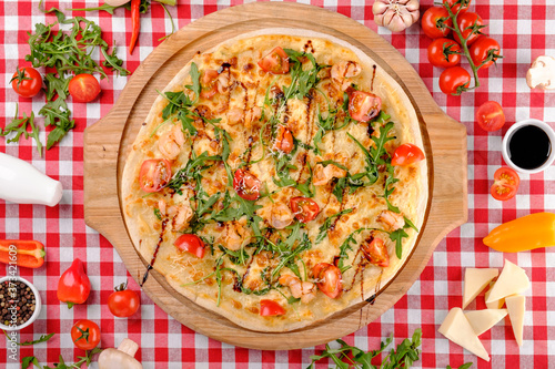Pizza with seafood, mozzarella, mussels, octopus, squid, salmon, shrimp, cheeseand, fresh rucola and tomatoes sauce in italian restaurant background, top view. Mediterranean food.