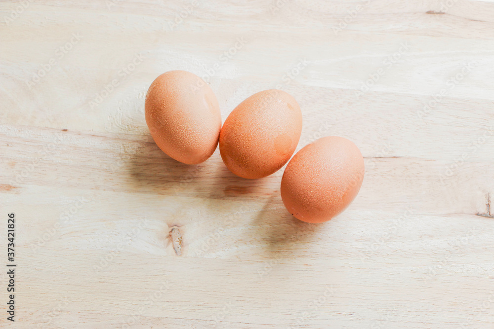 Three chicken eggs on a wooden cutting board Three chicken eggs on a wooden cutting board