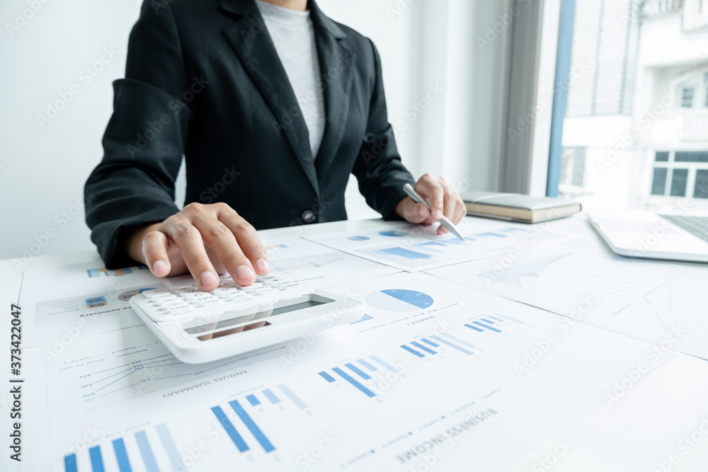 The hands of a male businesswoman use the calculator are analyzing and calculating the annual income and expenses in a financial graph that shows results To summarize balances overall in office The hands of a male businesswoman use the calculator are analyzing and calculating the annual income and expenses in a financial graph that shows results To summarize balances overall in office