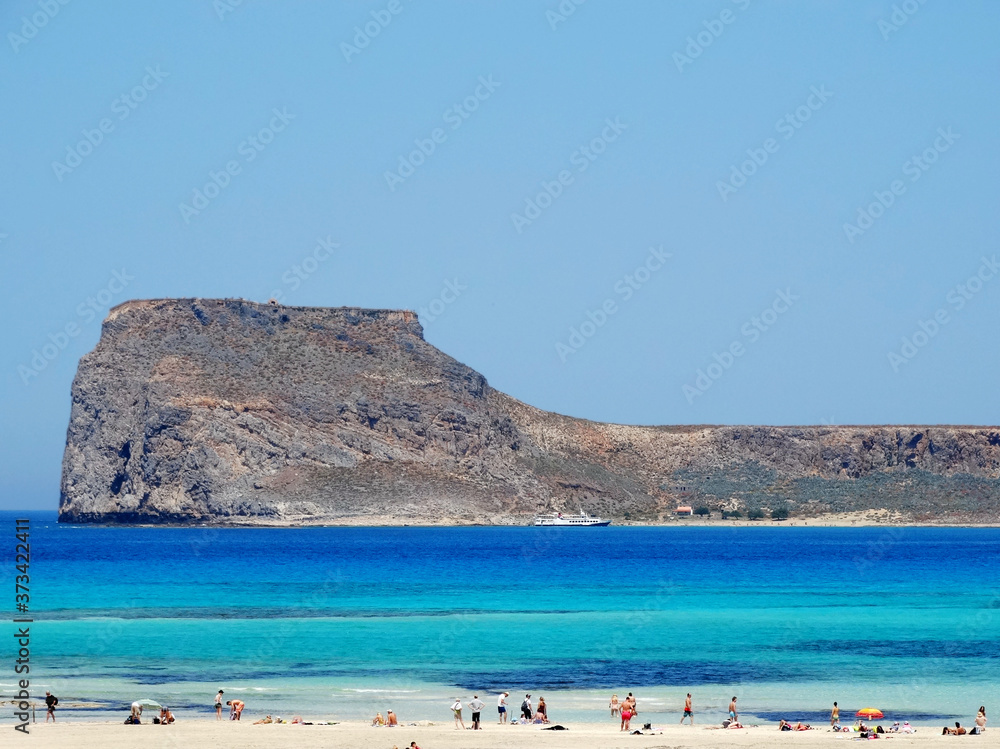 Tourists visit Balos in Crete, Greece and do sunbathing at the beach. The Gramvousa Peninsula forms the westernmost of the two pairs of peninsula in Crete and the western part of Kissamos Bay.
