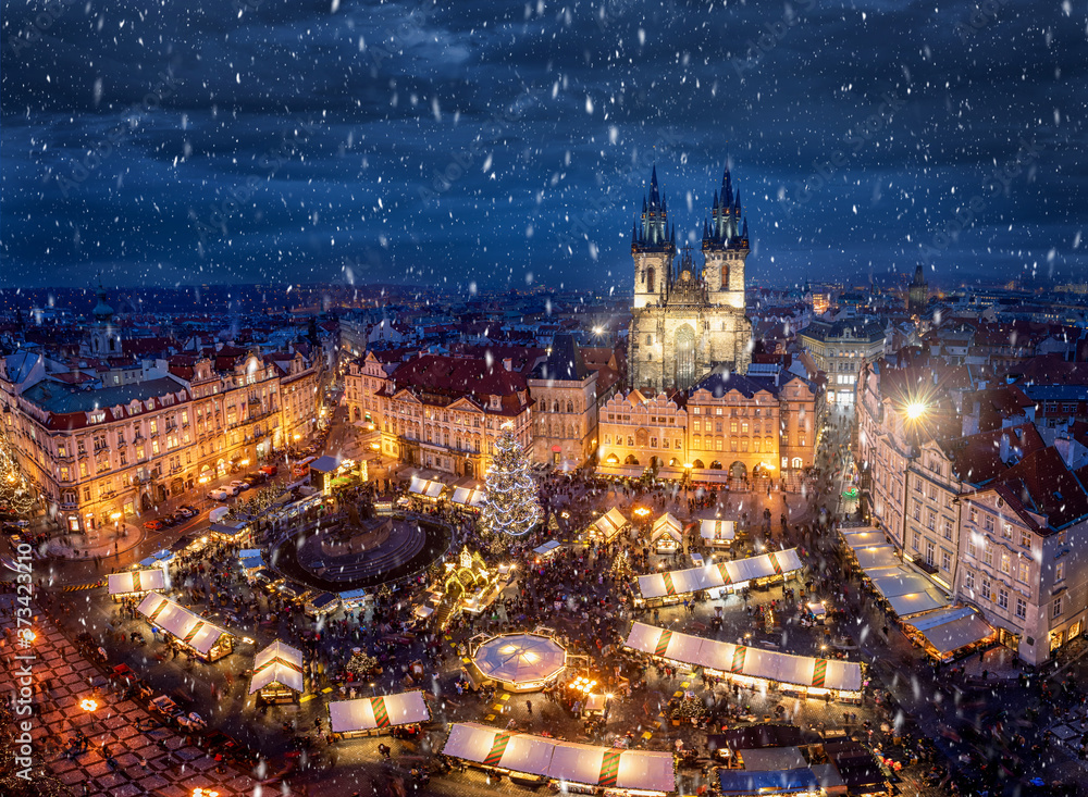 Der traditionelle Weihnachtsmarkt auf dem Platz in der Altstadt von Prag, Tschechien, mit festlicher Beleuchtung zur Adventszeit und Schneefall - obrazy, fototapety, plakaty 