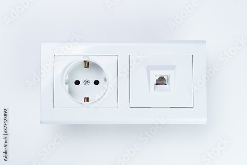 An electrical outlet and a white telephone socket are located side by side on a white background.