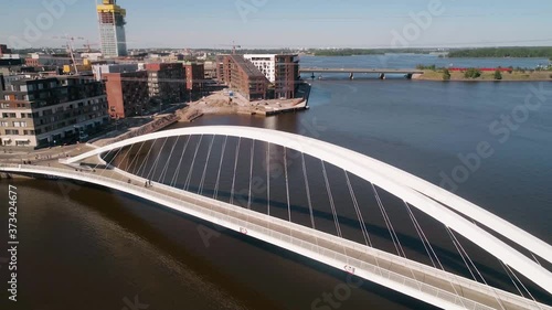 Aerial view overlooking people walking on the Isoisansilta bridge, on a sunny day, in Kalasatama, Helsinkii, Uusimaa, Finland - Orbit, drone shot photo