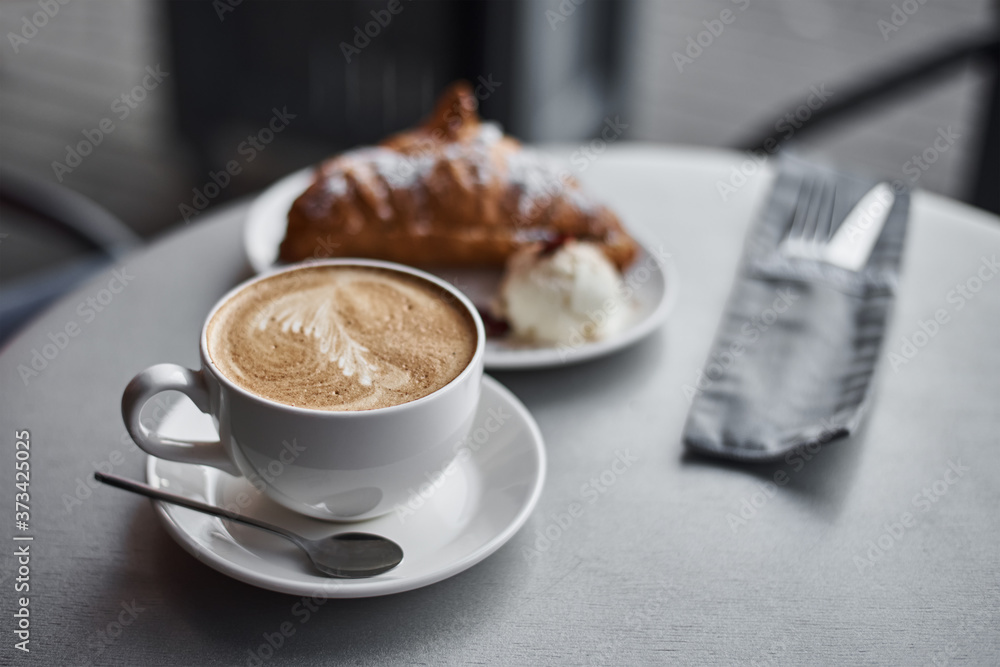Cup of coffee and croissant on table in cafe Cup of coffee and croissant on table in cafe