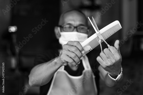 Black and white close-up male barber with comb and scissors.