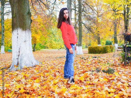 young girl on a background of fallen yellow foliage in the park