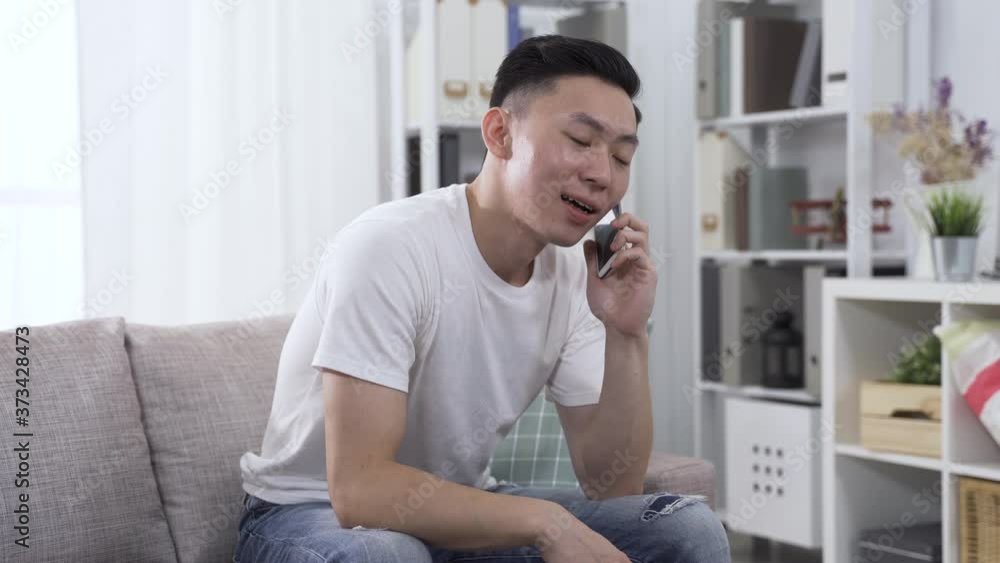 korean young male in parlor is answering a call from and catching up with an acquaintance happily. technology and communication concept korean young male in parlor is answering a call from and catching up with an acquaintance happily. technology and communication concept