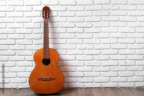 One guitar on the floor against white brick wall © fotofabrika