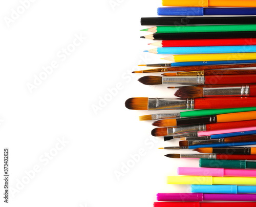 Paintbrushes, colorful pencils and felt markers pile isolated on white background, top view