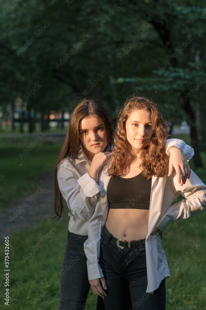 Two young caucasian girls walking in the park. Friendship concept Two young caucasian girls walking in the park. Friendship concept