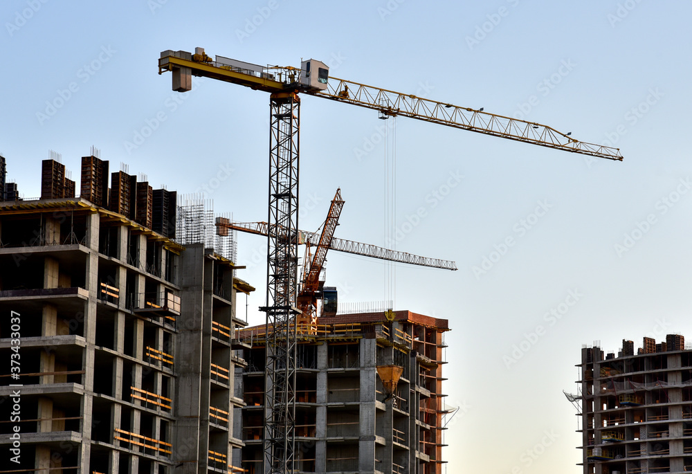 Preparing to pour a bucket of concrete into formwork.Tower crane lifting cement bucket during construction a multi-storey residential building. Construction cranes and builders in action Preparing to pour a bucket of concrete into formwork.Tower crane lifting cement bucket during construction a multi-storey residential building. Construction cranes and builders in action