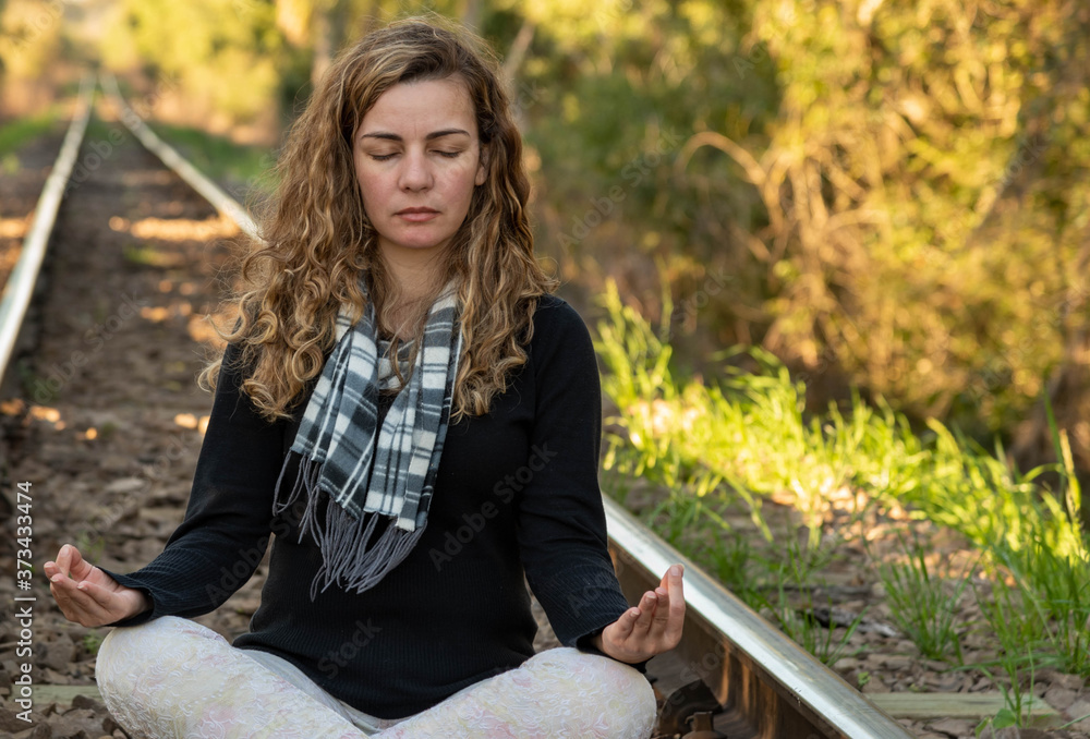 Blonde Brazilian woman meditating on the rails of a train line Blonde Brazilian woman meditating on the rails of a train line