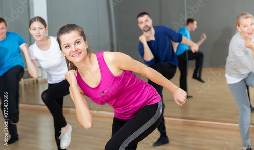 Portrait of dancing girl practicing vigorous swing during group training in dance studio