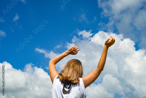 A woman, a girl stands backwards in a wheat field with her hands raised to the sky. High quality photo