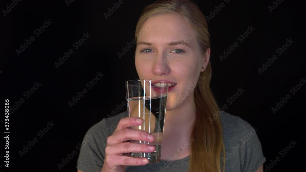 Drinking water. Young thirsty woman drinking mineral water from a glass with an expression of pleasure on her face. Hydration of the body. Water is part of a healthy diet. Drinking water. Young thirsty woman drinking mineral water from a glass with an expression of pleasure on her face. Hydration of the body. Water is part of a healthy diet.