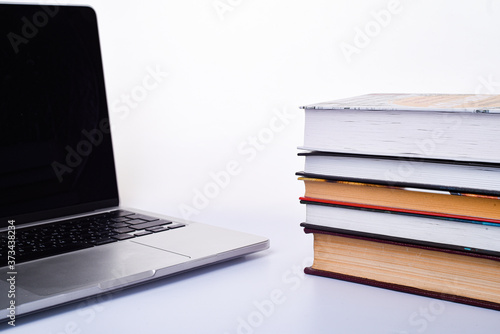 Laptop and stack of books on a white background. With space for letters or text. Quarantine and self-isolation concept
