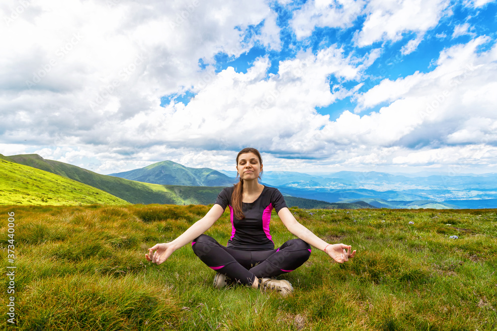 Happy young girl meditates, against the backdrop of beautiful mountains. Ukraine. Carpathians. Recreation.
