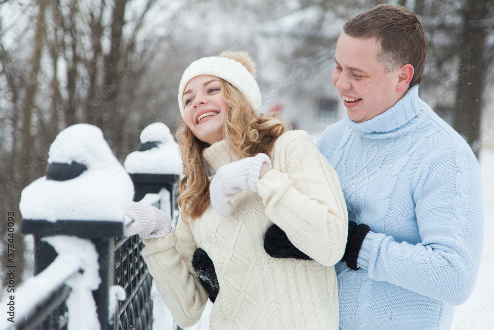 Young couple in knitted sweaters hugging in a winter park Young couple in knitted sweaters hugging in a winter park