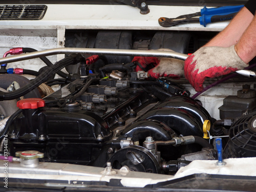 A car mechanic is engaged in repairing the car engine. Working professions, work in the service sector.