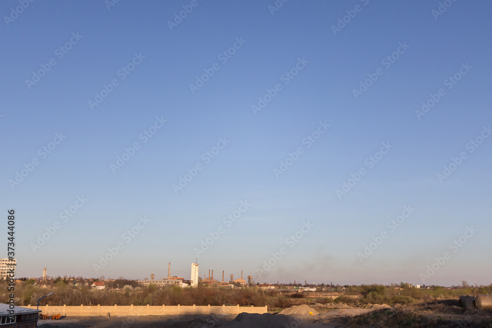 horizon of a blue sky with Abandoned factories and warehouses with their distinctive chimneys in Eastern Europe, in Pancevo, Serbia, former Yugoslavia, during a cold winter afternoon