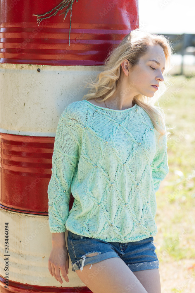 Beautiful young blonde posing in a knitted handmade sweater in nature
