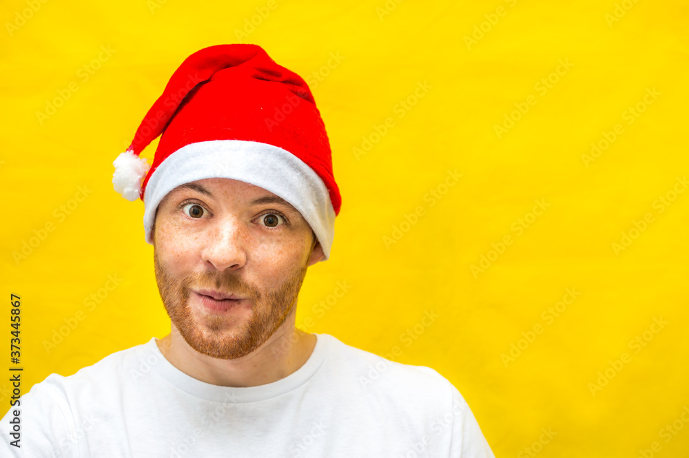 Portrait of a young handsome man in a santa claus hat on a yellow background. New Year 2021. Copy space Portrait of a young handsome man in a santa claus hat on a yellow background. New Year 2021. Copy space
