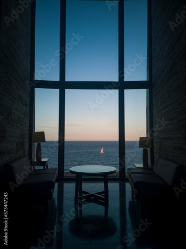 Sunset Meeting Space for Business with incredible views to the Sea while a Sailboat is crossing in front of the High Vertical Windows