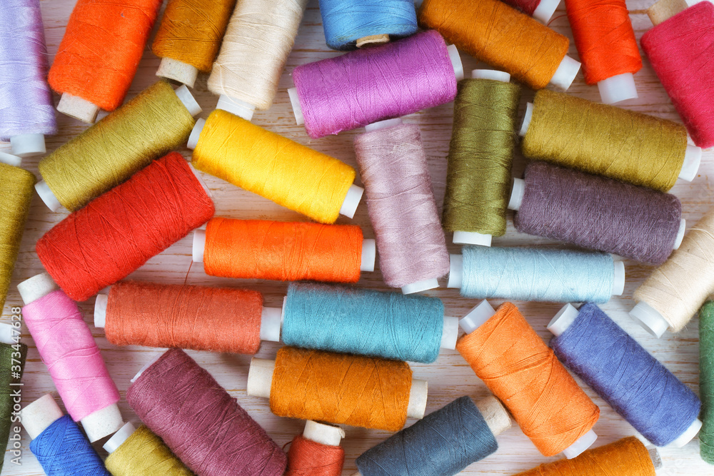 Multicolor sewing threads on white wooden background Multicolor sewing threads on white wooden background