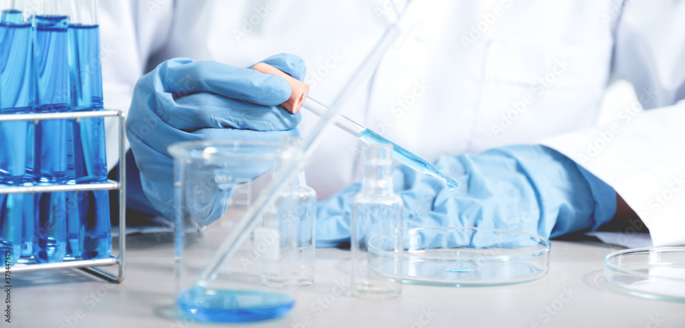 Fototapeta premium Scientists hold the pipette and drop the blue chemical liquid for research and analysis in a laboratory