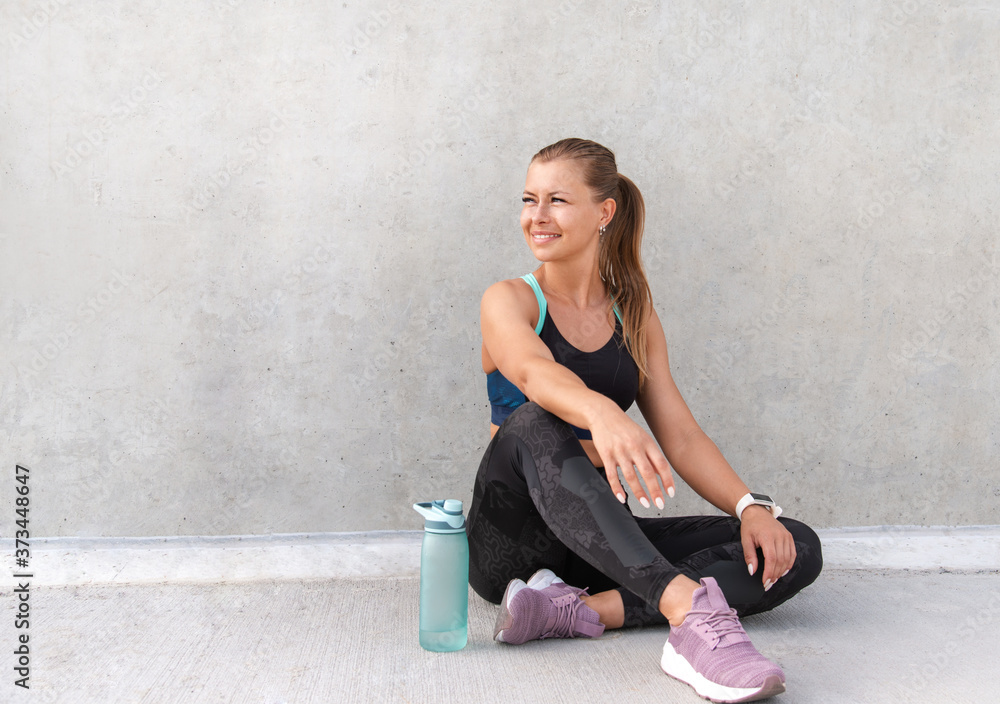 Fototapeta premium Fitness sporty woman is having a break after running early in the morning city at sunrise.