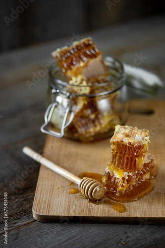 Pieces of fresh honeycomb with honey and glass jar on wooden background. Craft concept
