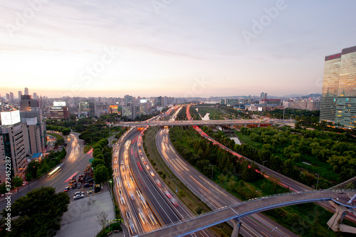 Colorful car light trails with motion blur effect bridge road with city building background