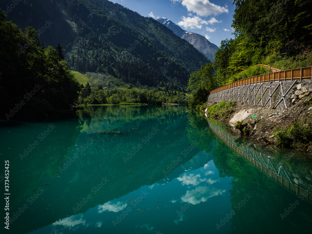 Scenic view on Klammsee near Kaprun, Austria, Europe. National park Hohe Tauern. Charming lake with amazing deep colorful water and wild clouds on sky. Scenic view on Klammsee near Kaprun, Austria, Europe. National park Hohe Tauern. Charming lake with amazing deep colorful water and wild clouds on sky.